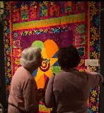 Threads That Bind Us participants look at a quilt.