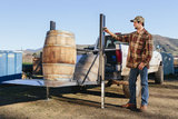 Man using LiftGator to lift large barrel on pickup truck