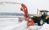 Tractor with front-mounted snow blower moving snow