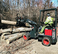 Man picking up logs with mini wheel loader grapple