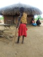 9-yr-old African girl, Aliru Sevia, on crutches with a broken leg - in front of hut