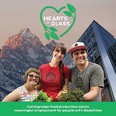 Hearts of Glass poster - 2 women and one man with disabilities standing in front of a tall building with mountains in the background