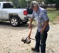 Picture of a man standing in a gravel driveway  holding a piece of firewood with the LogOx Tool