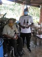 Photo of 2 African men - 1 in wheelchair and the other standing - holding bottles of wine