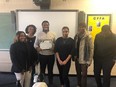 3 female and 3 male African American NCA&T students standing in a row with a whiteboard in the background and one of them holding a certificate.