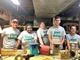 Pic of 5 people standing in a basement shop in front of a table with homemade bird houses and other crafts on it. They are all wearing gray t-shirts that say -  plant for a change.