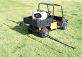 Black and yellow utility vehicle with white sprayer tank in back connected by hose to sprayer boom on back of vehicle sitting in green grass field
