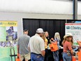 3 women & 2 men standing in front of AgrAbility display tables with black curtain in background Dee Jepsen talking to them from behind tables