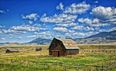 Barn with split-rail fence and mountains and clouds in background