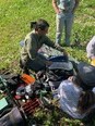 Ned Stoller kneeling on ground unpacking assistive technology devices with 3 people around him