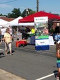 NC AgrAbility pop-up banner outside red canvas roofed tent at China Grove with people walking on street in foreground