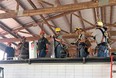 9 men in hard-hats under tin roof practicing grain bin entrapment extrication