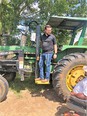 Man in blue jeans & dark t-shirt on John Deere tractor step listening to African American man in wheelchair in foreground