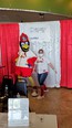 Woman in blue jeans and white shirt next to large red mascot bird - Fredbird - of the St Louis Cardinals with white & red curtain background