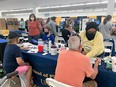 2 people behind table doing health screening of 2 people seated in front of table at MO State Fair