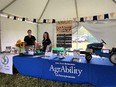 Kendra Martin on L and Abbie Spackman on Rt behind blue AgrAbility table display with toy blue tractor on table