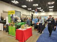 Green & yellow AgrAbility banner with display table draped in red in foreground & many people going by display at FFA Convention