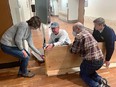 4 people putting together a wood raised-bed garden box inside of a building