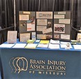 Table with many brochures and a stand-up display on it - covered with a gray tablecloth saying BRAIN INJURY ASSOCIATION OF MISSOURI