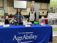 2 women standing behind display table with blue tablecloth saying PENN STATE EXTENSION AGRABILITY FOR PENNSYLVANIANS - in large expo room