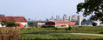 Photo of red and white barns in foreground with skyline of Columbus OH in background.