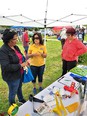 Betty Rodriguez in center under a tent talking with 2 ladies about AgrAbility & gardening 