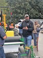 African American man Finis Stribling outside next to tractor demonstrating it to TN New Farmer Academy students