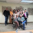 Picture of 10 CO and NM AgrAbility staff with 2 of them seated & 8 standing against a wall with 3 net-design square pieces of art on it