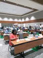 Many people - primarily African American - at long tables in a large room working with papers.