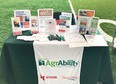 Green cloth-covered table with Nebraska AgrAbility materials on it in a green field
