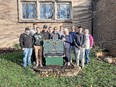 11 people standing outside building behind Alpha Gamma Rho sign