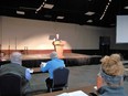 Man - Steve Engleking - at podium in large room with 3 people seated in foreground with backs to the camera