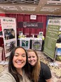Selfie of 2 young women in front of GA AgrAbility booth.