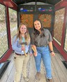 Two young women holding hatchets in hatchet-throwing arcade