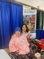 Woman in wheelchair with Betty Rodriguez standing behind her at NC AgrAbility booth