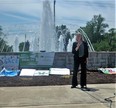 Karen Funkenbusch standing and speaking in front of fountain with sign in background reading MY MENTAL HEALTH