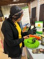 A young African American woman trying on an assistive technology glove at a display table