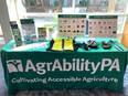 Display table covered with an AgrAbility PA cloth with assistive technology & literature on it  