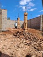 Mutumba Faisal standing inside beginnings of a cement brick building