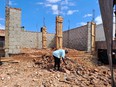 Mutumba Faisal looking at rubble at site of new cement brick building