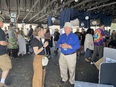 Bill Field speaking with a woman in a large pole barn filled with people