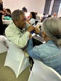 An African American man and woman working together at a table with other people at tables in the background