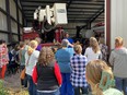 People standing outside a large farm shed listening to a man explain about his farm equipment