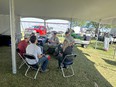 Capstone students with Bill Gary all sitting in a circle under a large white tent