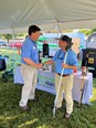 Troy Dugger shaking hands with man in front of TN AgrAbility display table under white tent