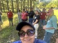 A group of people with Betty Rodriguez in the foreground standing in a woods.