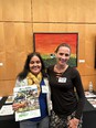 Beatriz Rodriguez & Danielle Pennington smiling at the camera in front of an AgrAbility table