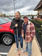 Sam Seavey & Jason Barber - 2 men with blindness - standing outside on a sidewalk under cloudy skies.