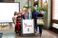 A group of 6 people including Esme Mandujano on the right standing next to a De Colores sign at the Cultivemos Salud farmworker retreat.