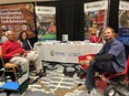 3 people sitting at the NC AgrAbility booth at the NC Sustainable Agriculture Conference.